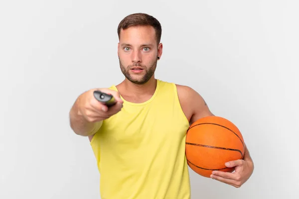 Schöner Mann Mit Basketballball Und Wahl Eines Kanals Mit Controller — Stockfoto