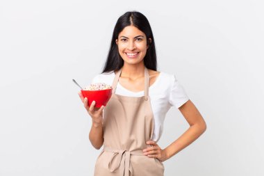 Güzel İspanyol kadın güzel İspanyol şef kadın mutlu bir şekilde gülümsüyor kalçasında ve kendinden emin ve elinde mısır gevreği kasesi var.