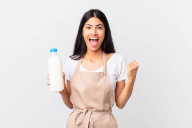 Güzel İspanyol aşçı kadın şok olmuş, gülüyor, başarıyı kutluyor ve elinde bir süt şişesi tutuyor.
