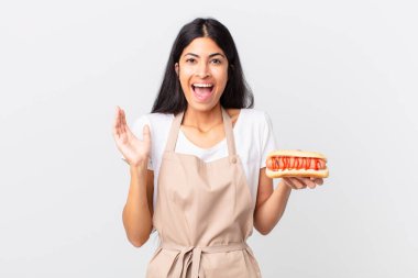 İspanyol güzel kadın güzel İspanyol şef kadın kendini mutlu ve şaşkın hissediyor. İnanılmaz bir şey ve elinde sosisli sandviç var.