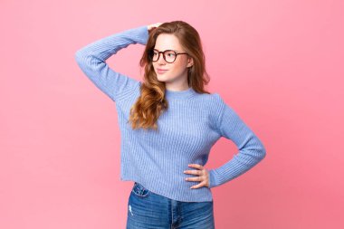 Güzel kızıl saçlı kadın şaşkın ve kafası karışık, kaşınan kafa