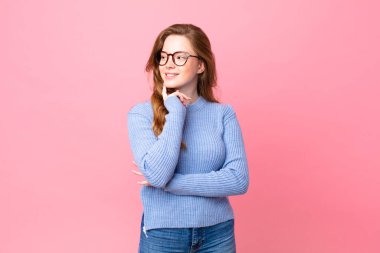 Güzel kızıl saçlı kadın mutlu bir şekilde gülümsüyor ve hayal kuruyor.