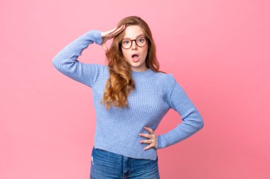 Güzel kızıl saçlı kadın mutlu, şaşkın ve şaşkın görünüyor.