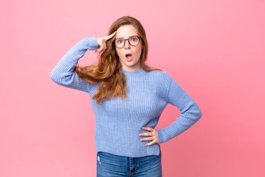 Güzel kızıl saçlı kadın şaşırmış görünüyor, yeni bir düşünce, fikir ya da konsept keşfediyor.