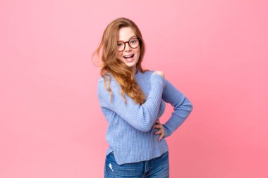 Güzel kızıl saçlı kadın kendini mutlu hissediyor ve meydan okumayla yüzleşiyor ya da kutluyor.