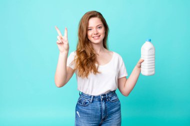 Gülümsüyor ve arkadaş canlısı görünüyor, ikinciyi gösteriyor ve elinde bir süt şişesi tutuyor.