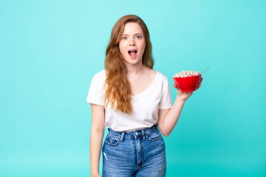 Güzel kızıl saçlı kadın şok olmuş ya da şaşırmış görünüyor ve elinde bir kahvaltı kasesi tutuyor.