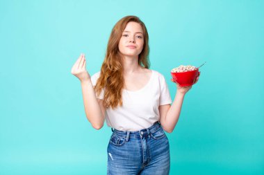 Güzel kızıl saçlı kadın kapiş ya da para hareketi yapıyor. Sana ödemeni söylüyor ve elinde bir kâse tutuyor.