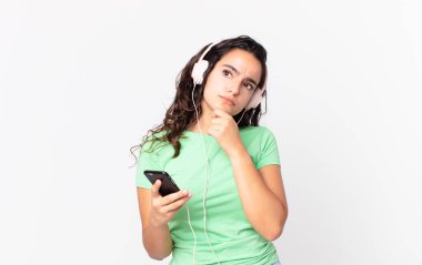 Düşünen, kuşkulanan, kulaklıkla ve akıllı telefonuyla kafası karışmış İspanyol bir kadın.