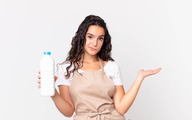 İspanyol aşçı kadın şaşkın, şaşkın, şüpheci ve elinde bir süt şişesi tutuyor.