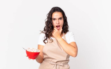 İspanyol asıllı güzel bir kadın. Güzel bir şef. Ağzı ve gözleri açık, elleri çenesinde ve elinde kahvaltı kasesi olan.