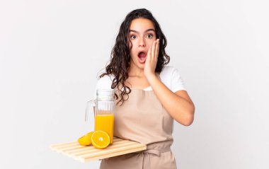 İspanyol güzel aşçı kadın şok olmuş, korkmuş ve elinde portakal suyu tutuyor.
