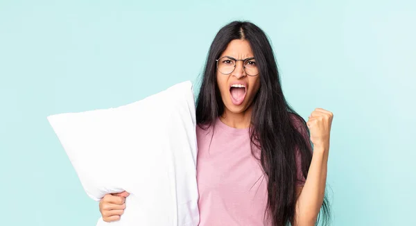怒りの表情で積極的に叫び枕でパジャマを着ているかなりヒスパニック系女性 — ストック写真