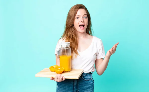 Pretty Red Head Woman Feeling Extremely Shocked Surprised Holding Orange — Stock Photo, Image