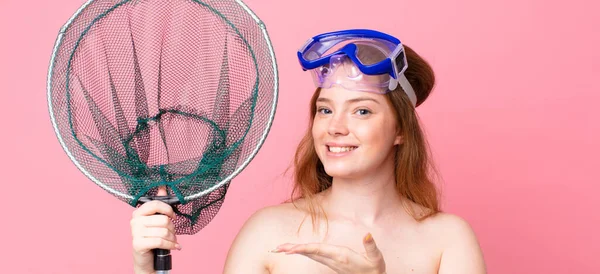 红头发的女人兴高采烈地笑着 感到快乐 并带着一副鱼网护目镜来展示自己的想法 — 图库照片