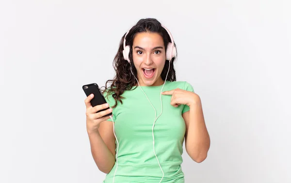 Довольно Латиноамериканка Чувствует Себя Счастливой Указывая Себя Возбужденным Наушниками Смартфоном — стоковое фото