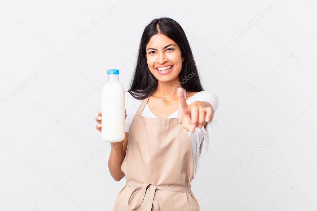 pretty hispanic chef woman smiling proudly and confidently making number one and holding a milk bottle