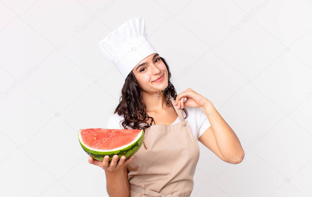 hispanic pretty chef woman looking arrogant, successful, positive and proud and holding a watermelon