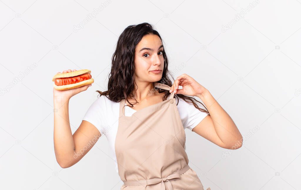 hispanic pretty chef woman looking arrogant, successful, positive and proud and holding a hot dog