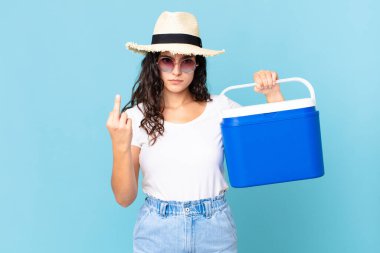 Güzel İspanyol bir kadın kızgın, sinirli, asi ve saldırgan bir şekilde portatif bir buzdolabı tutuyor.