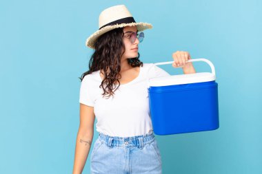 Profildeki güzel İspanyol kadın portatif bir buzdolabı hayal ediyor, hayal ediyor ya da hayal ediyor.