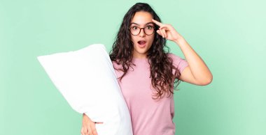Güzel İspanyol kadın şaşırmış görünüyor, yeni bir düşünce, fikir ya da konsept fark ediyor ve yastıkla pijama giyiyor.