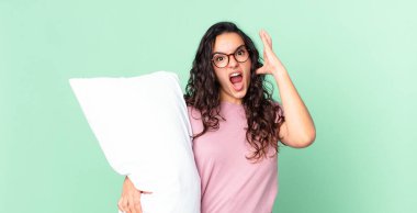 Güzel İspanyol kadın ellerini havaya kaldırıp bağırıyor ve yastıklı pijama giyiyor.