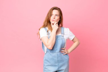 Kızıl saçlı güzel kadın düşünüyor, kuşkulu ve şaşkın hissediyor.