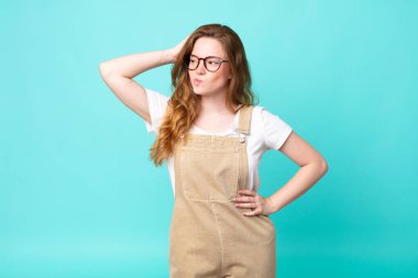 Güzel kızıl saçlı kadın şaşkın ve kafası karışık, kaşınan kafa