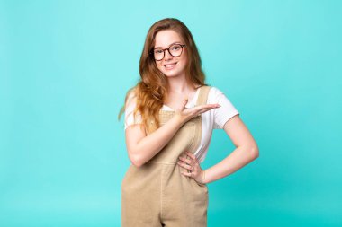 Güzel kızıl saçlı kadın neşeyle gülümsüyor, mutlu hissediyor ve bir konsept gösteriyor.