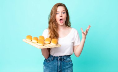 Kızıl saçlı güzel bir kadın şok olmuş ve şaşırmış hissediyor ve elinde bir çörek tutuyor.