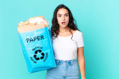 İspanyol güzel kadın şok olmuş ya da şaşırmış görünüyor ve elinde geri dönüşümlü bir kese kağıdı tutuyor.