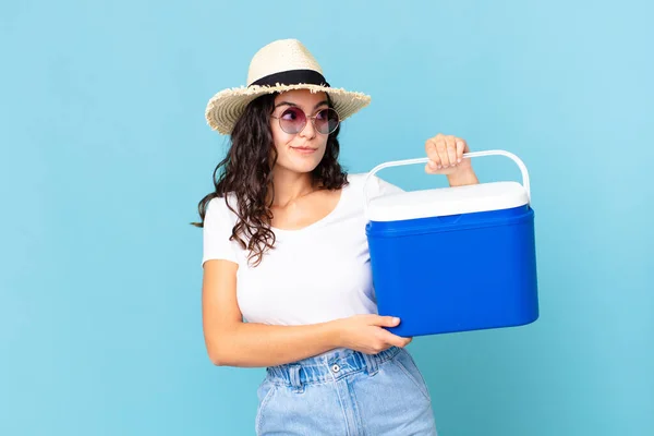 Pretty Hispanic Woman Shrugging Feeling Confused Uncertain Holding Portable Refrigerator — Stock Photo, Image