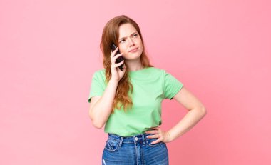 Kızıl saçlı güzel kadın akıllı telefonunu kullanıyor.