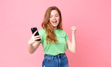 Kızıl saçlı güzel kadın akıllı telefonunu kullanıyor.