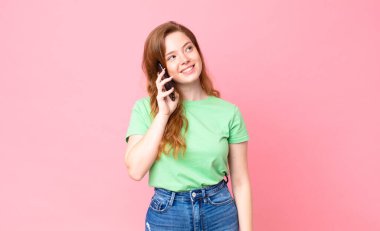 Kızıl saçlı güzel kadın akıllı telefonunu kullanıyor.