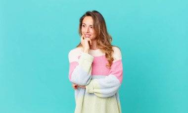 Güzel bir kadın mutlu, kendinden emin bir ifadeyle gülümsüyor, elleri çenesinde.