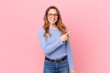 Güzel bir kadın neşeyle gülümsüyor, mutlu hissediyor ve bir tarafı işaret ediyor.