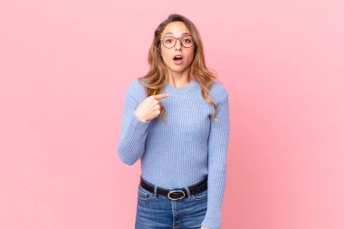 Şok olmuş ve ağzı açık, kendini işaret eden güzel bir kadın.