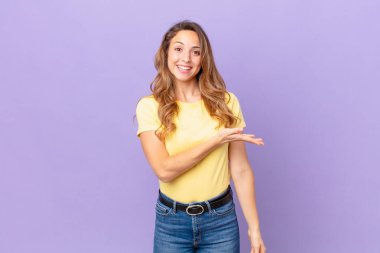 Güzel bir kadın neşeyle gülümser, mutlu hisseder ve bir konsept gösterir.