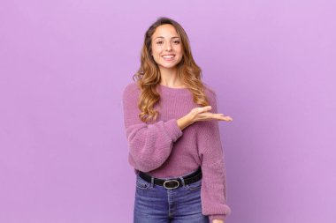 Güzel bir kadın neşeyle gülümser, mutlu hisseder ve bir konsept gösterir.