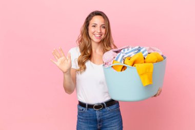 Güzel bir kadın mutlu bir şekilde gülümsüyor, el sallıyor, seni selamlıyor ve elbiselerini yıkıyor..