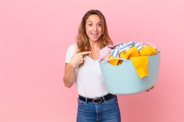 Güzel bir kadın heyecanlı ve şaşırmış görünüyor. Yan tarafı gösteriyor ve çamaşırları yıkıyor..