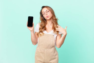 Güzel bir kadın stresli, endişeli, yorgun ve hayal kırıklığına uğramış ve elinde bir akıllı telefon tutuyor.