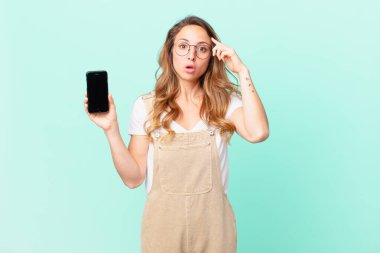 Güzel kadın şaşırmış görünüyor, yeni bir düşünce, fikir ya da konsept fark ediyor ve elinde bir akıllı telefon tutuyor.