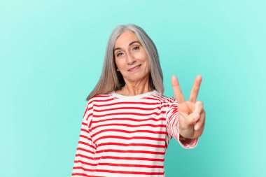 Orta yaşlı beyaz saçlı kadın gülümsüyor ve arkadaş canlısı görünüyor.