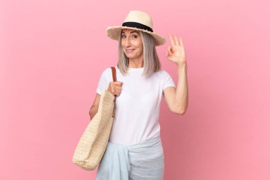 Orta yaşlı beyaz saçlı kadın kendini mutlu hissediyor, iyi bir jestle onaylıyor. yaz konsepti