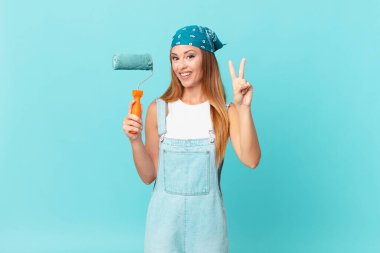 Güzel bir kadın gülümsüyor ve arkadaş canlısı görünüyor. İki numara yeni bir ev duvarı boyuyor.