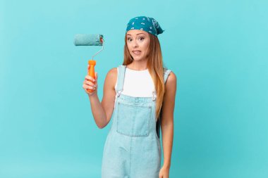 Güzel bir kadın kafası karışmış ve yeni bir ev duvarı boyuyor.