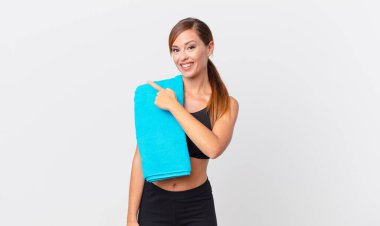 Güzel bir kadın neşeyle gülümsüyor, mutlu hissediyor ve bir tarafı işaret ediyor. fitness konsepti